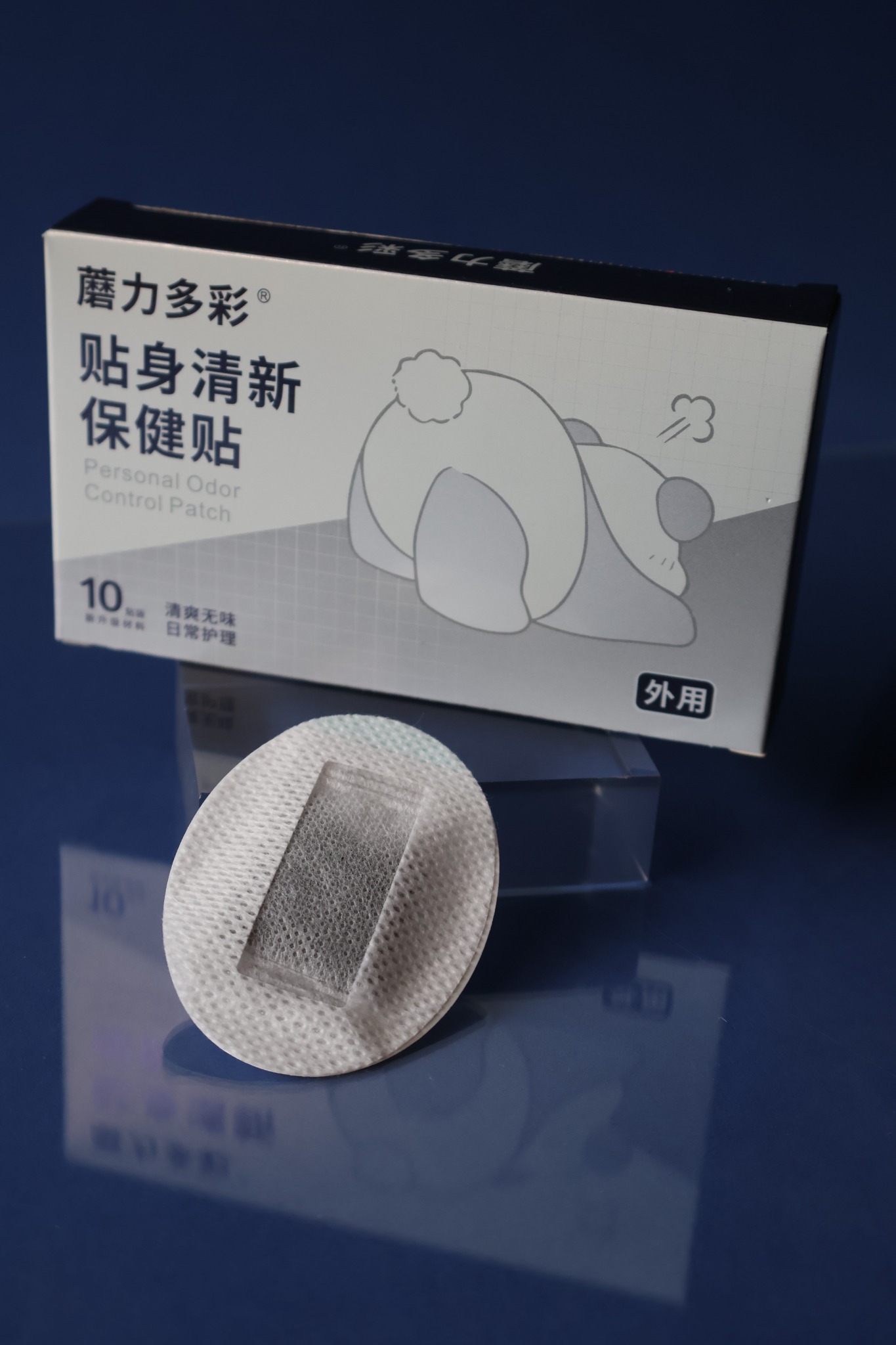 MOLIDUOCAI packaging and a single patch displayed together on a reflective navy surface, with the panda identity on the box.