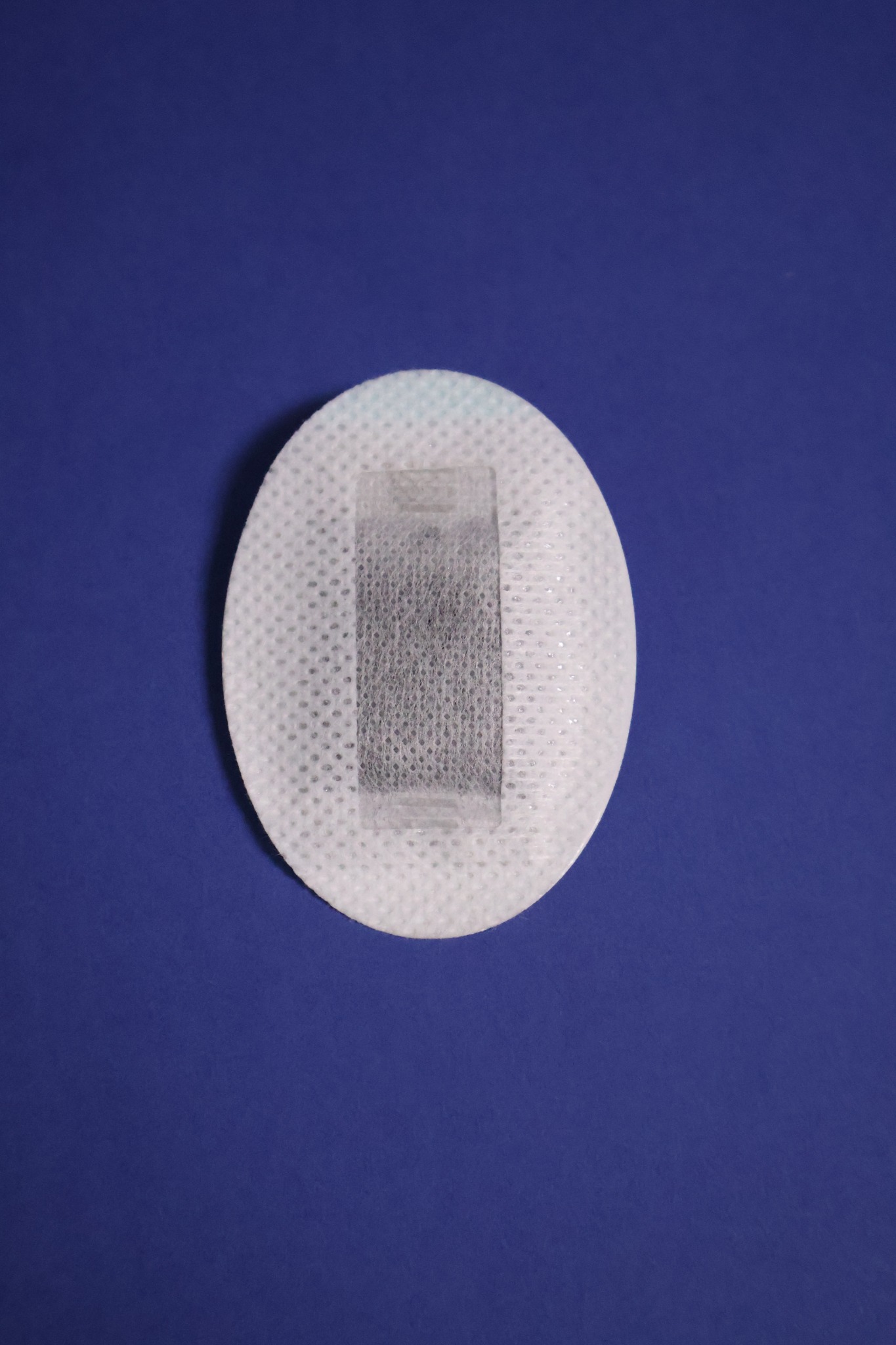 Front view of the oval patch on navy, showing the fabric carrier and rectangular filtration pouch.